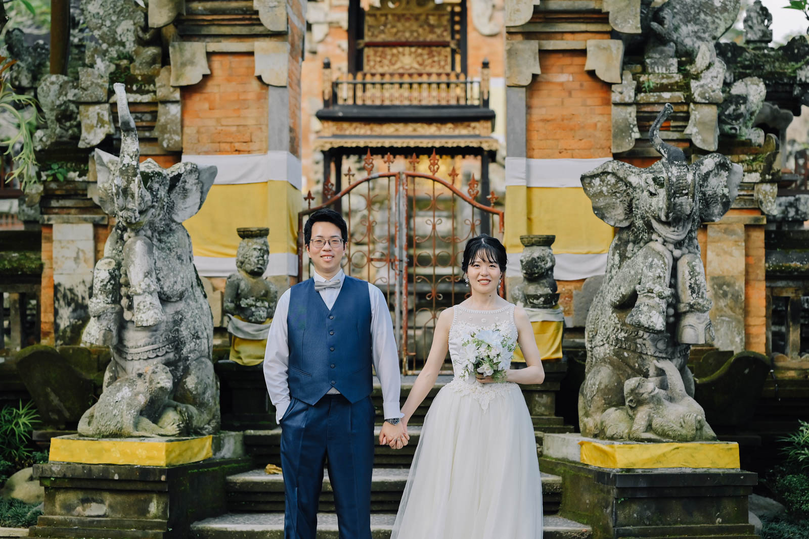 バリの伝統的な寺院門の前に立つ新郎新婦