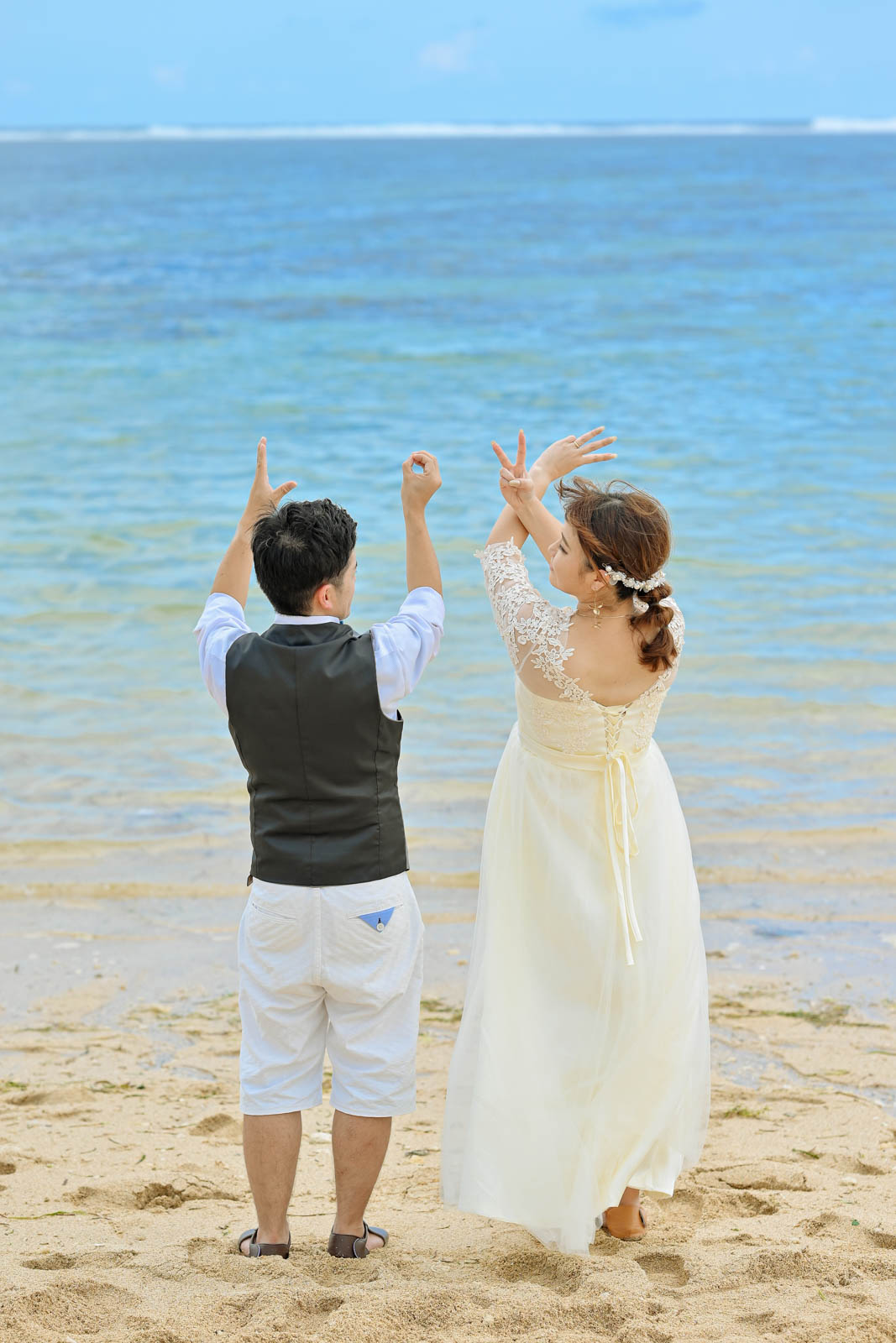 バリ島のビーチで新郎新婦が背中を向けてLOVEポーズをつくる前撮りショット