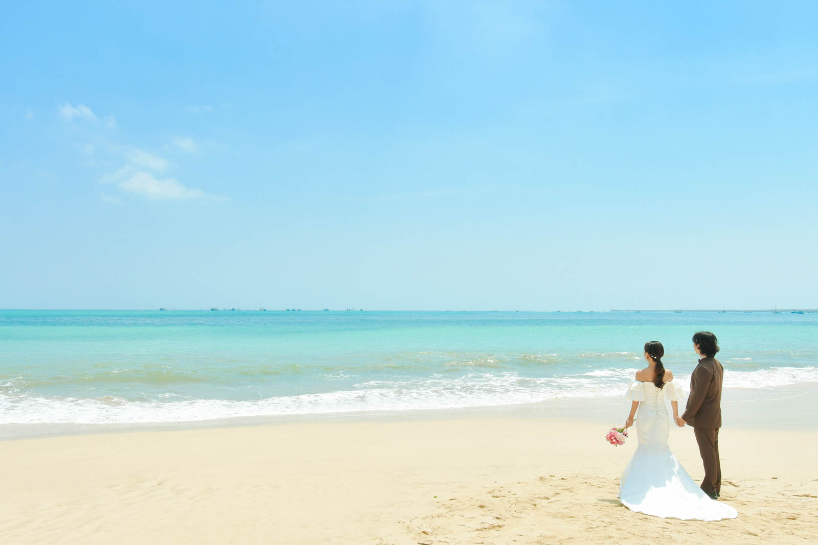 バリ島ジンバランビーチで手を取り合い海を見つめる新郎新婦のフォトウェディング