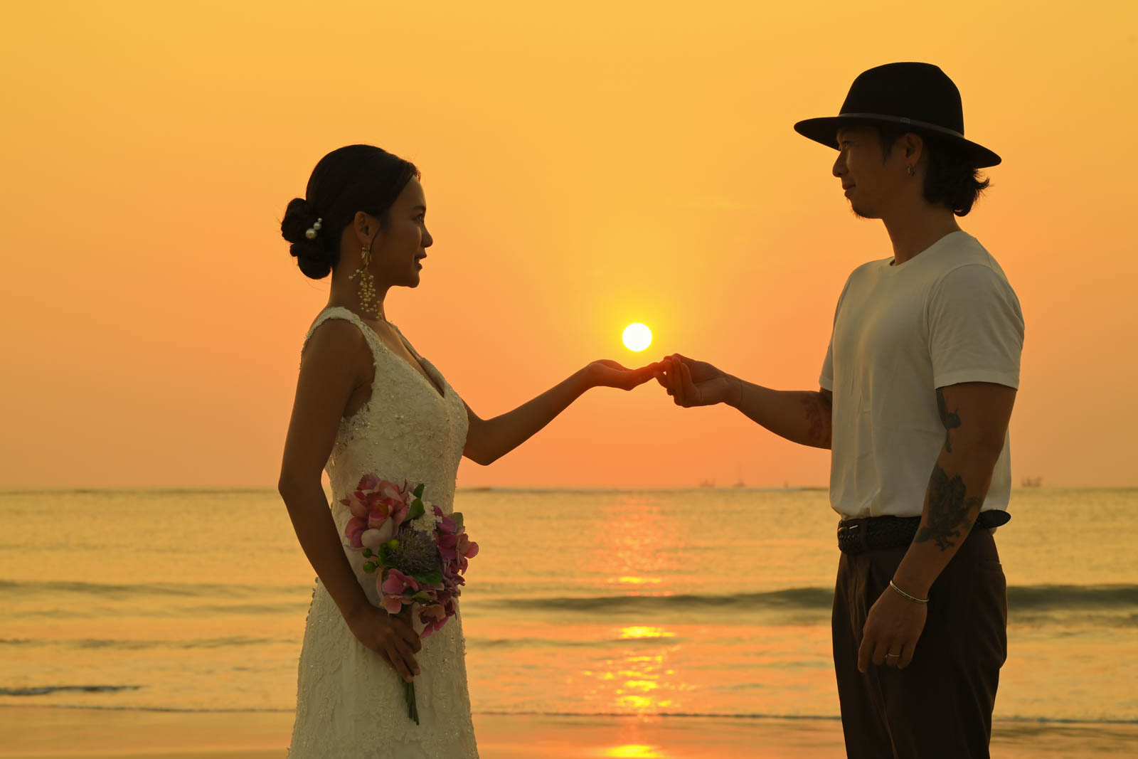 サンセットを手に乗せるポーズをするロマンチックなサンセットフォト