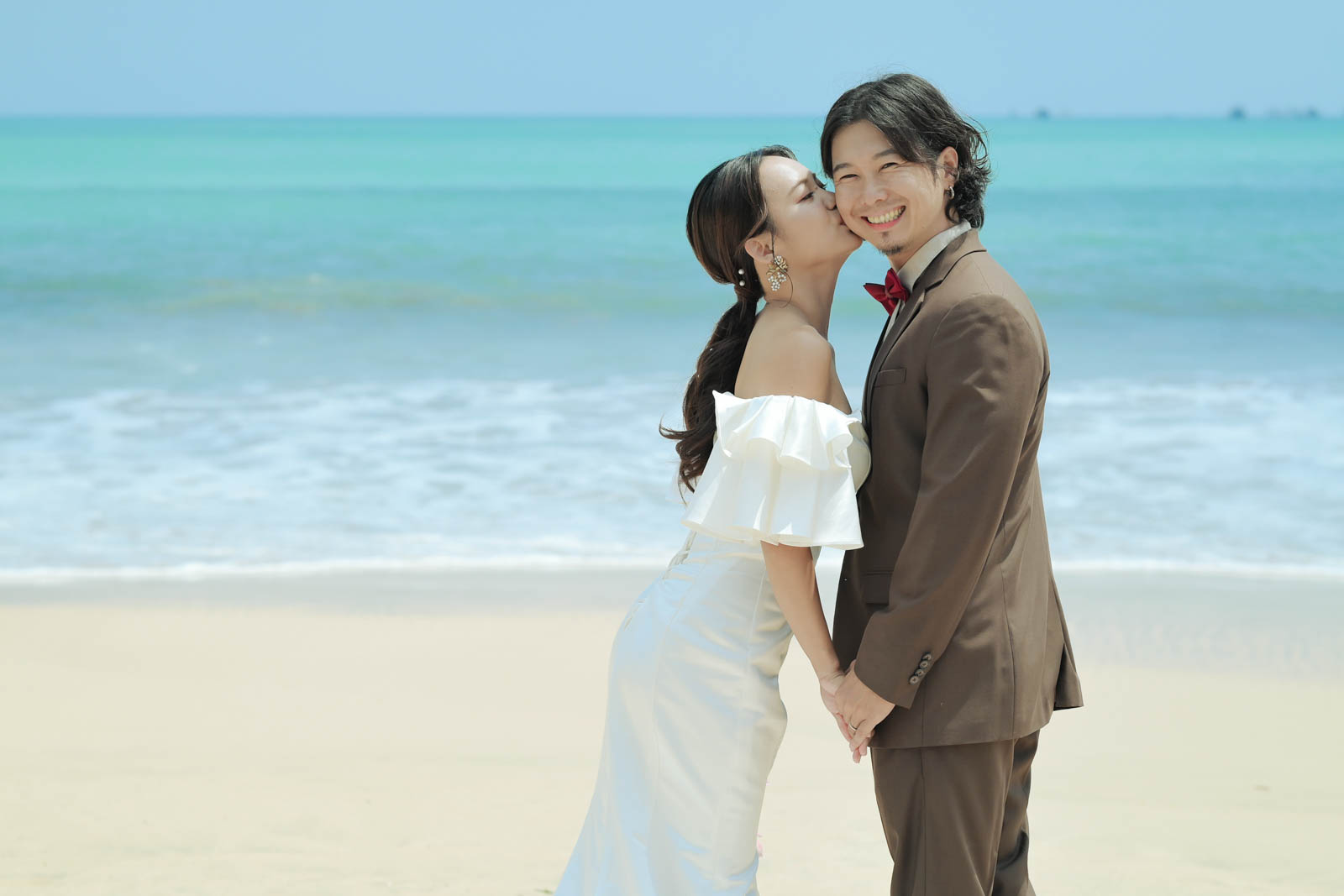 ジンバランビーチで花嫁momokoさんが新郎ホリくんに頬キスする幸せなフォトウェディングショット